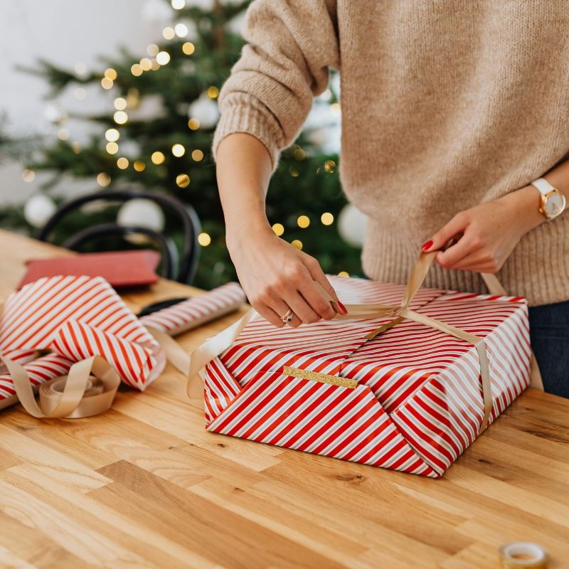 Woman ties bow on wrapped gift