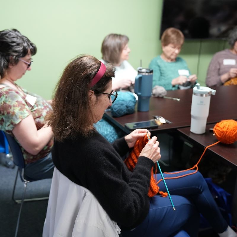 Group around tables work on various fiber projects at library temporary location